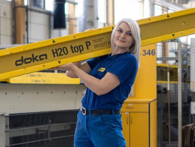 Female team member of Doka production holding a formwork beam
