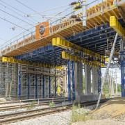 Blick von unten auf Brückenbaustelle, Traggerüst-Unterstellung mit gelb-blauen Doka UniKit-Trägern sowie Staxo-Traggerüst.